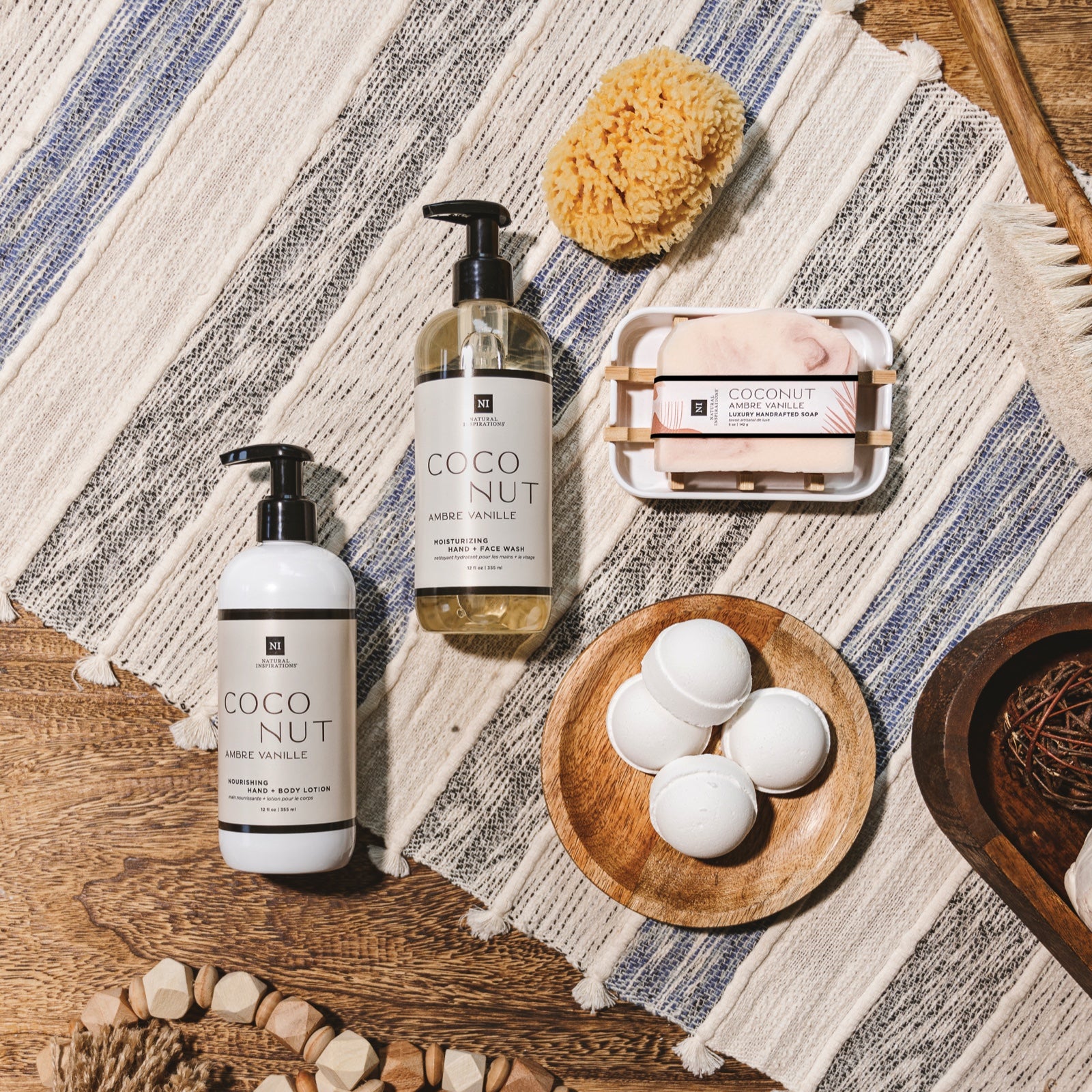 overhead view of coconut ambre vanille products on a wood table with a table runner and various bath products scattered throughout