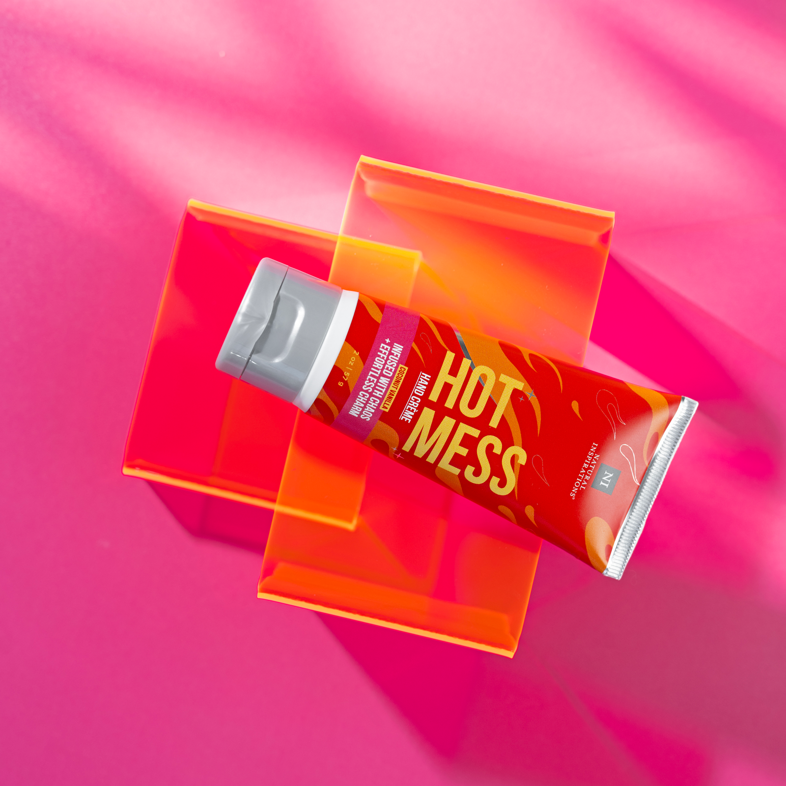 overhead view of a hot mess mini hand cream on a hot pink background