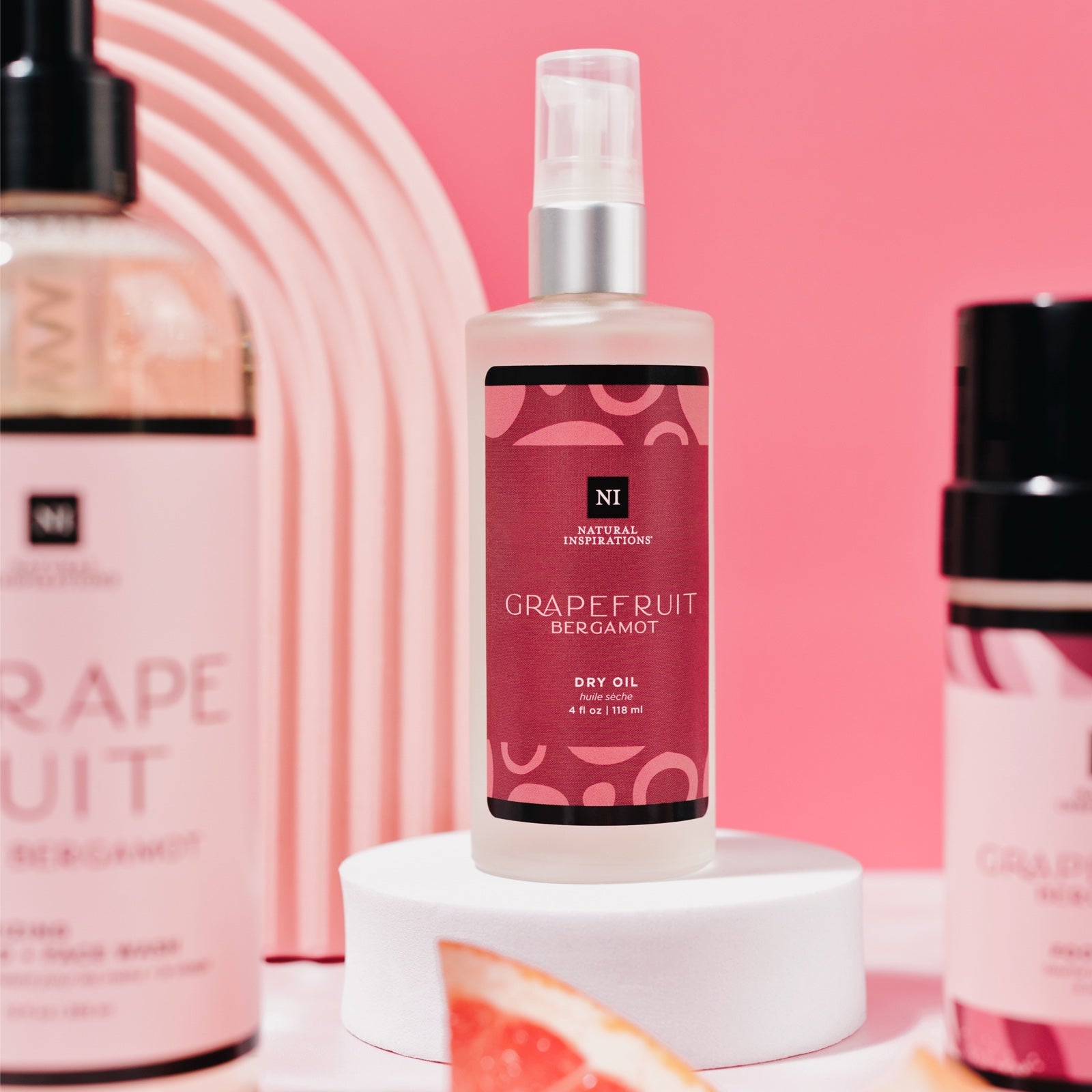 close up of grapefruit bergamot dry oil on a pink background with other grapefruit products in the foreground