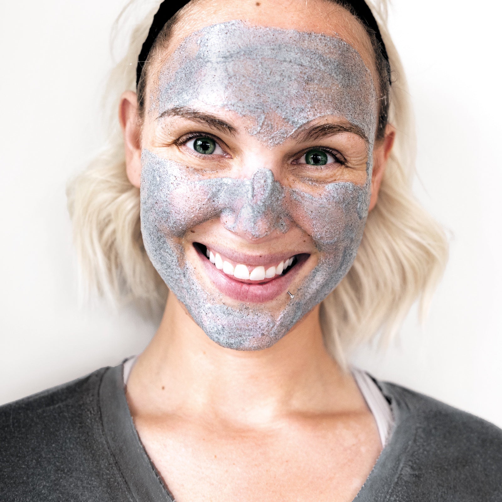 close up of a smiling woman's face covered in coconut ambre vanille body and face scrub