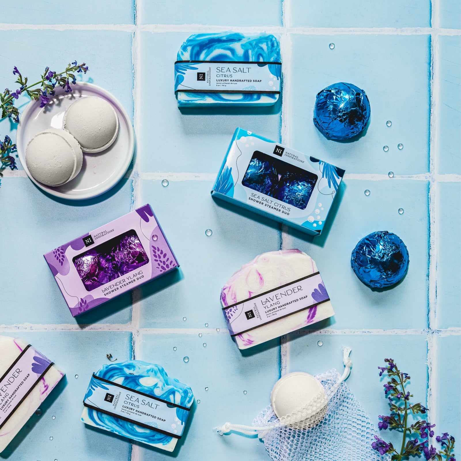 overhead image of shower steamers and handcrafted soaps on a blue tile background