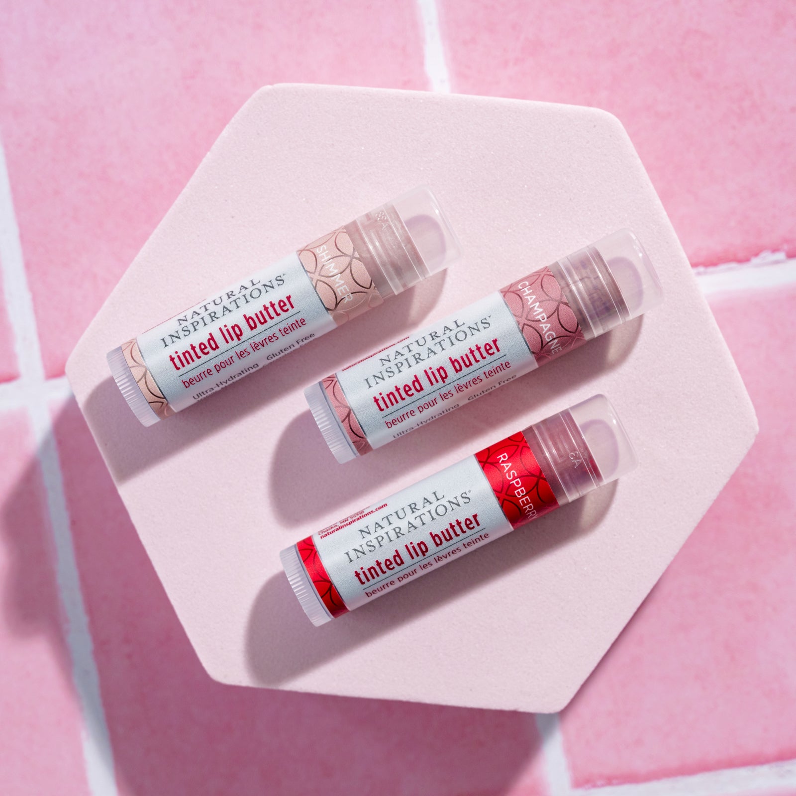 overhead view of 3 lip tints on a pink tile background