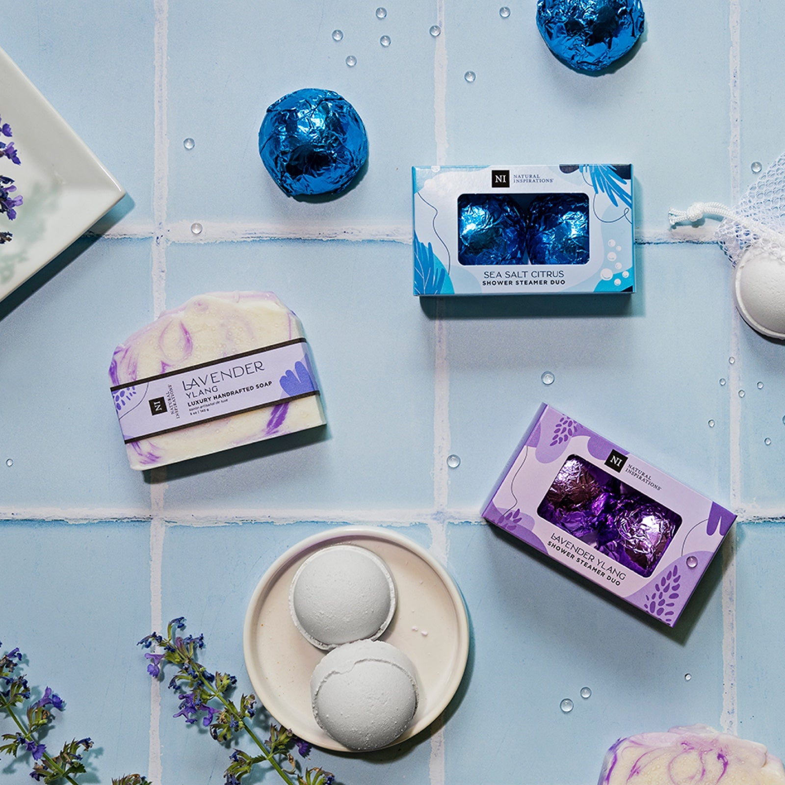 overhead image of shower steamers and handcrafted soaps on a blue tile background
