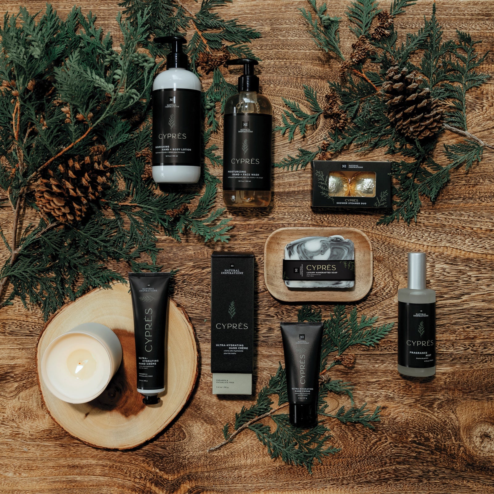 overhead view of cypres products on a wood background with pinecones and cypress branches scattered throughout.