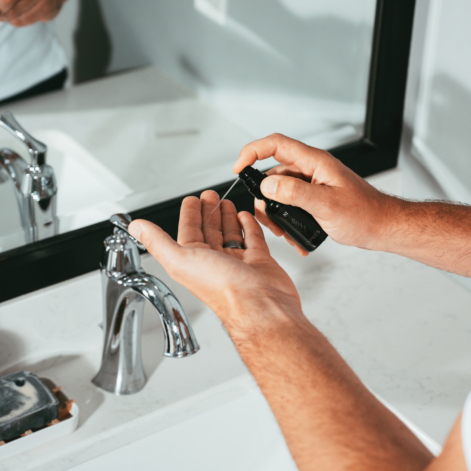 man pumping beard oil into his hand prior to applying in a bathroom setting