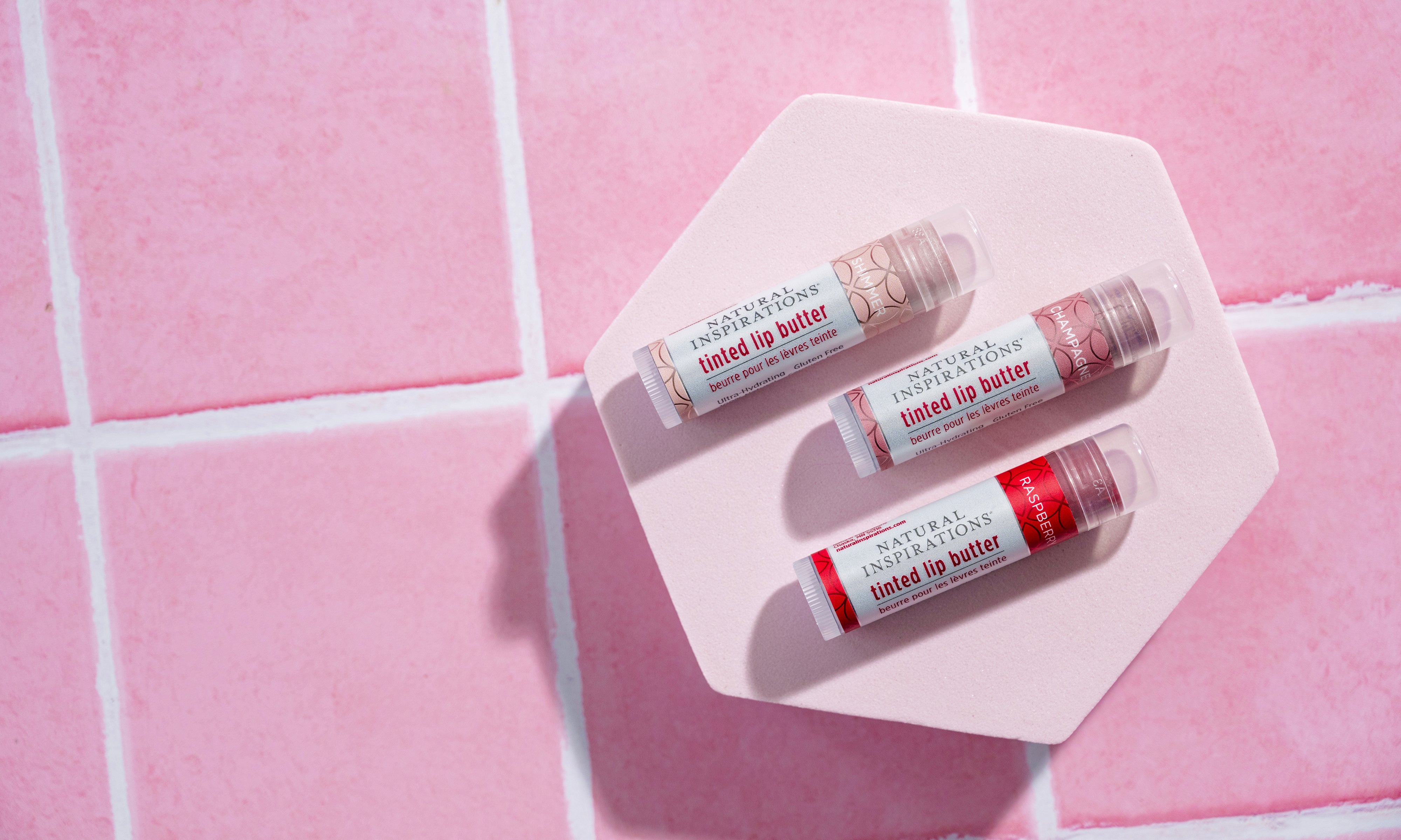 overhead view of 3 lip tints on a pink tile background