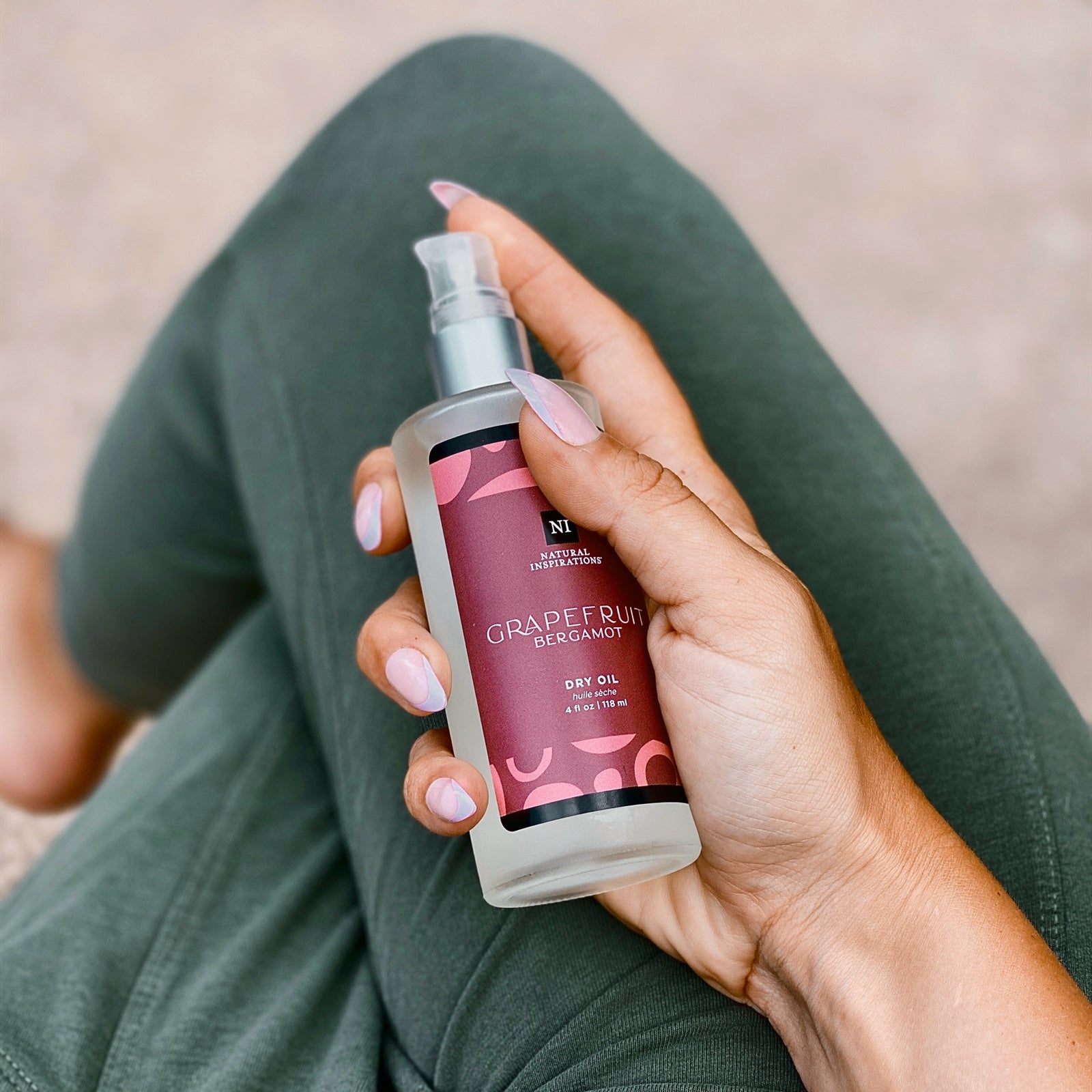 woman holding a grapefruit bergamot dry oil in her lap