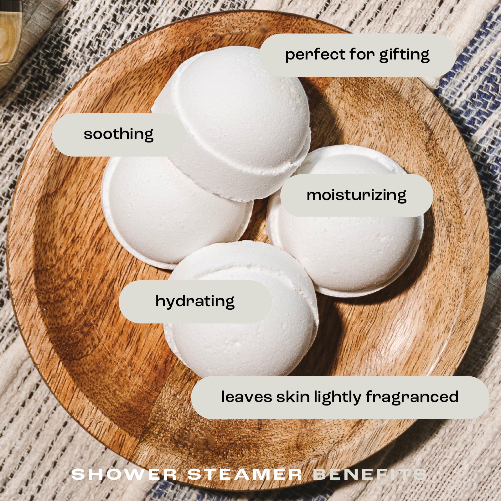 overhead view of shower steamers in a dish on a fabric background with the listed benefits: perfect for gifting, soothing, moisturizing, hydrating and leaves skin lightly fragranced