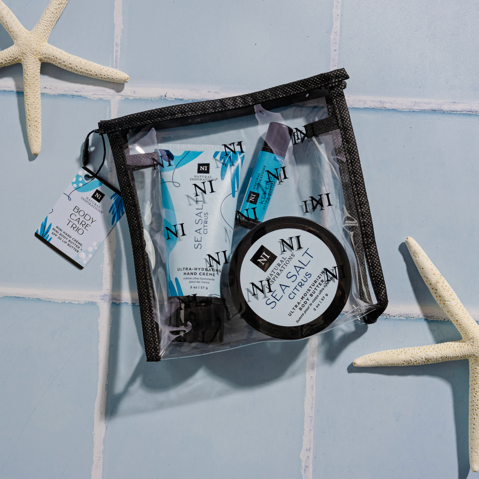 overhead view of Sea Salt Citrus Body Care Trio on a blue tile background with seashells and a starfish scattered in the background