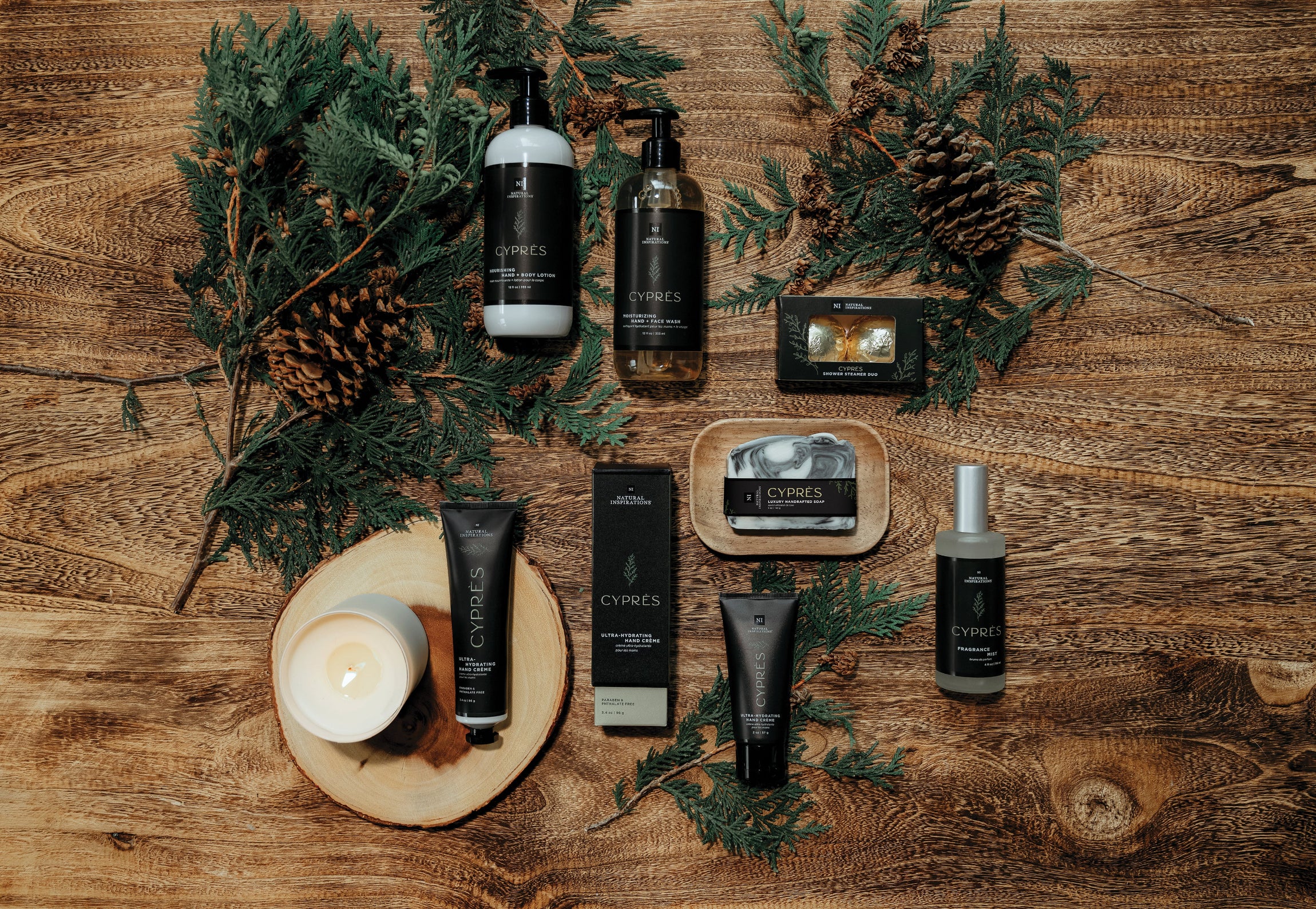 overhead view of cypres products on a wood background with pinecones and cypress branches scattered throughout